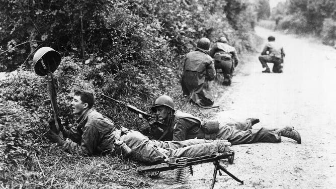A U.S. patrol hiding behind bushes during clashes in the countryside of Normandy. Normandy, June 1944.