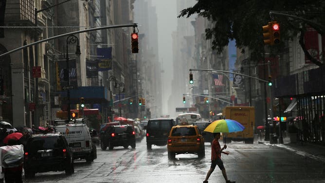 NEW YORK, NY - JUNE 22: A man walks through the rain during an intense afternoon thunderstorm on June 22, 2012 in New York City. The storm brought relief to two days of oppressively hot weather in New York and much of the East Coast where high heat warnings and air quality alerts had been issued from Quebec to Virginia.