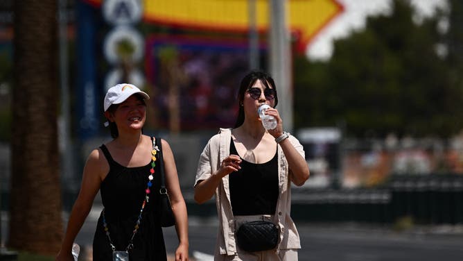 A person drinks a bottle of water while walking in the heat in Las Vegas, Nevada, on July 30, 2023, as temperatures reach more than 100 degrees Fahrenheit (37.78C). July is on track to be the hottest month in recorded history, scientists confirmed on July 27, as UN chief Antonio Guterres warned Earth has moved into an "era of global boiling".