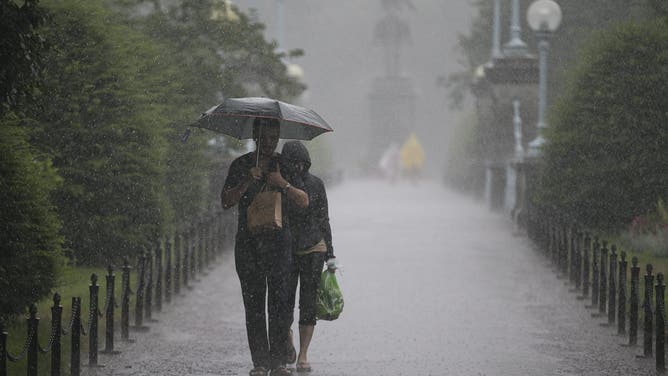 BOSTON - JULY 23: Sylvain Goyette and Trinh Hoac of Montreal walked in the Public Garden after purchasing an umbrella when heavy rains hit the area. A flash flood formed on Charles Street between Boston Common and the Public Garden in Boston, Tuesday, July 23, 2013.