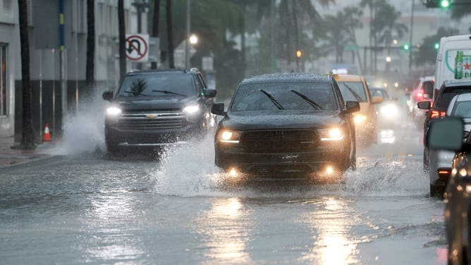 MIAMI BEACH, FLORIDA - JUNE 12: Vehicles make their way through a flooded street on June 12, 2024 in Miami Beach, Florida. Flood concerns are rising in Florida as tropical moisture passes through the area.