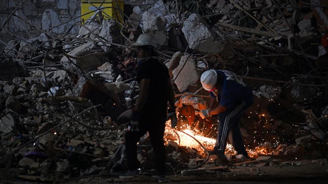 A rescuer cuts the steel bars of a collapsed building with an angle grinder in Caracas on June 25, 2026, following deadly earthquakes. 