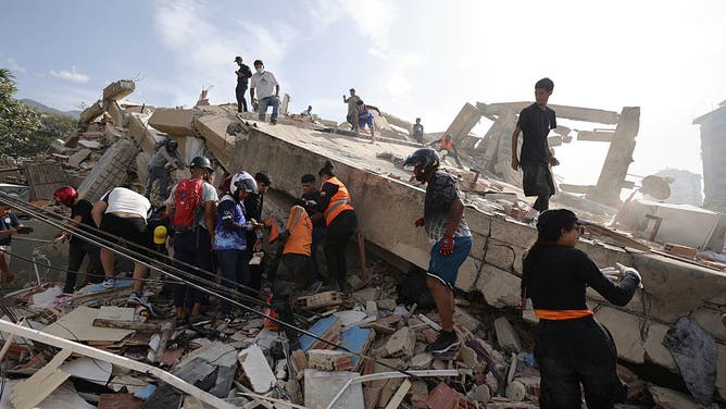 LA GUAIRA, VENEZUELA - JUNE 25: People and rescuers search for victims amid debris of demolished buildings as rescue efforts continue after a magnitude 7.2 earthquake struck Venezuela and other regions in the Caribbean on June 25, 2026 in La Guaira, Venezuela.