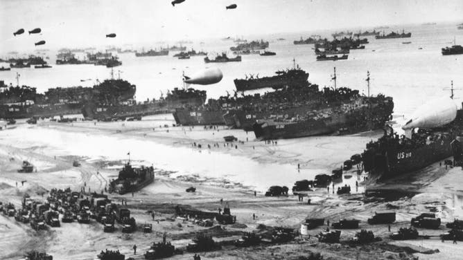 14th July 1944: Fleets of US transport and landing craft disgorge reinforcements and supplies for the US troops who liberated the Contentin peninsula, the deep-water port of Cherbourg and the communication centre of La Haye du Puits. Barrage balloons float overhead as protection against German strafing aeroplanes, which did not appear.