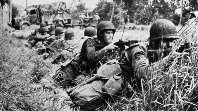 American fighting men, pressing closely on the heels of retreating Germans in the Battle of Normandy, take cover in a ditch at St. Sauveur-le-Vicomte as they return the enemy fire with rifles and machine guns. | Location: St. Sauveur-le-Vicomte, France.