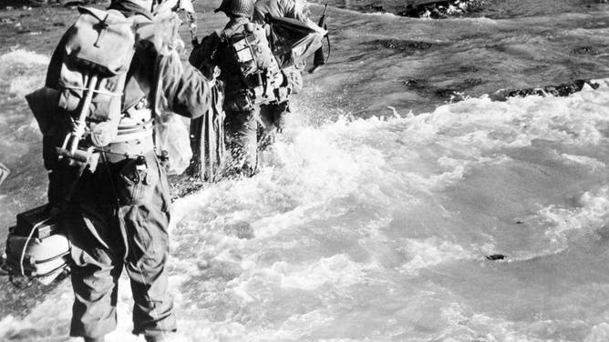 View of a line American soldiers as they wade ashore from their landing craft, Normandy, France, June 14, 1944.