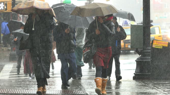 UNITED STATES - APRIL 15: Pedestrians shield themselves with umbrellas as they walk down a rain soaked street in the Brooklyn borough of New York on Sunday, April 15, 2007. A spring storm with sheeting rains and gusty winds moved into the northeastern U.S. today, canceling some weekend events and threatening highway and airline travel at the start of the workweek.