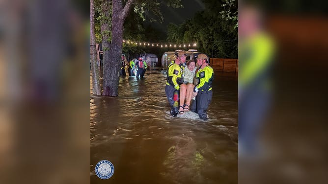 Texas Game Wardens, along with the SAR team, carry residents out of rising floodwaters in Central Texas Saturday.