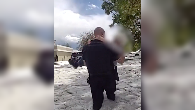 Aurora Police officer safely carries the woman out of the deep, hail-covered floodwaters.