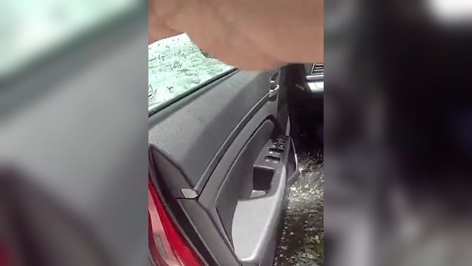 The officer opens the car door as water comes pouring in.
