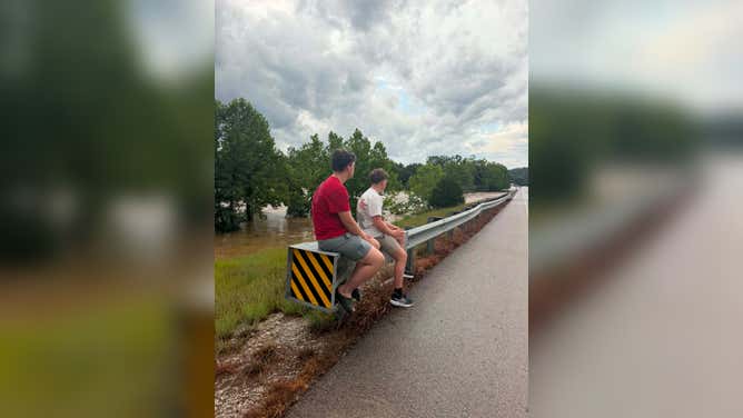 People sit on a guard rail after being evacuated due to flooding in Lesterville, MO.