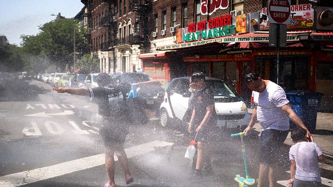 A family cools off at a fire hydrant in the Hamilton Heights neighborhood in the Manhattan borough of New York City on July 2, 2026. Blistering temperatures and humidity gripped swaths of the United States on July 1, with the worst yet to come for the densely populated East Coast as the nation co-hosts the World Cup and prepares to celebrate its 250th birthday.