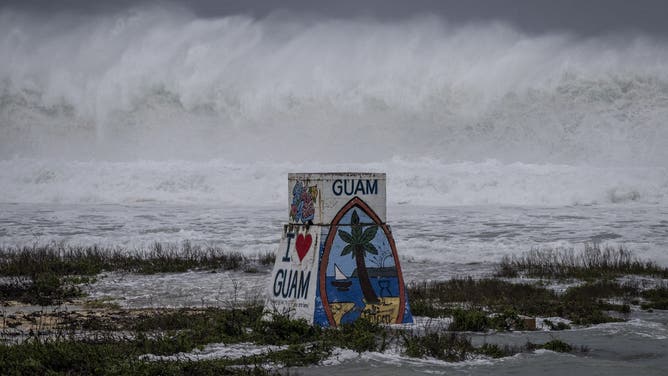 High waves crash against the coastline at a beach as the forecasted Super Typhoon Bavi approaches in Guam on July 5, 2026. People in Guam and the Northern Marianas moved to emergency evacuation centers and made last-minute preparations on July 5, hours before a "super typhoon" was projected to bulldoze through the US Pacific territories.