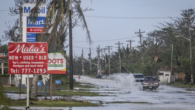 Motorists commute through a flooded road after heavy rain brought by Super Typhoon Bavi in Guam on July 7, 2026.