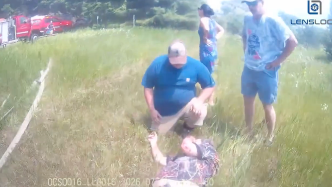 A member of law enforcement evaluates the driver on the ground to see if he's injured.