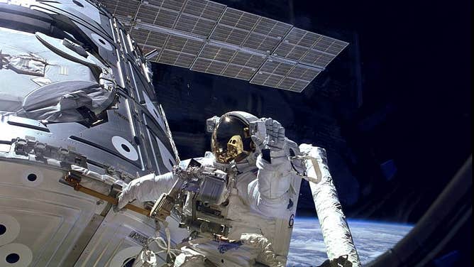 Astronaut James H. Newman waves during a spacewalk.