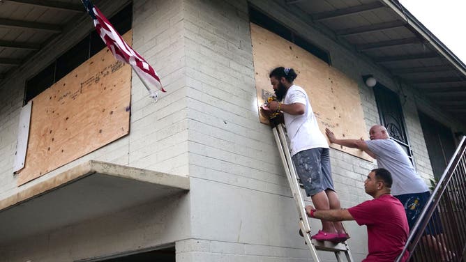(From L) Mapu Obrien, Jack Obrien, and Masta Obrien board up the windows of their home in preparation for hurricane Douglas in Honolulu, Hawaii, on July 25, 2020. Douglas is expected to be a category 1 hurricane with winds 74 to 95mph (119 to 152kph), as it approaches the islands this weekend.