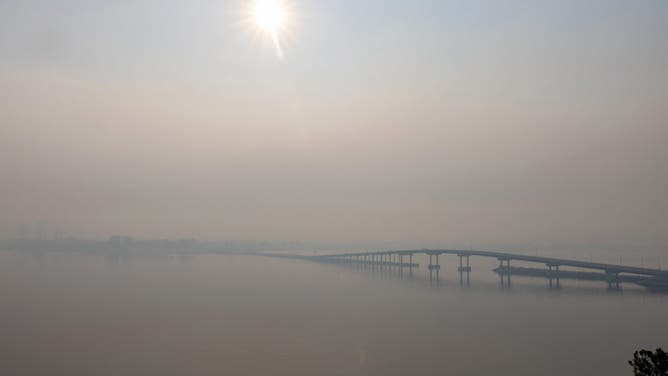 TOPSHOT - Smoke hangs around the William R. Bennett Bridge as the nearby McDougall Creek fire continues to burn in West Kelowna, British Columbia, on August 19, 2023.