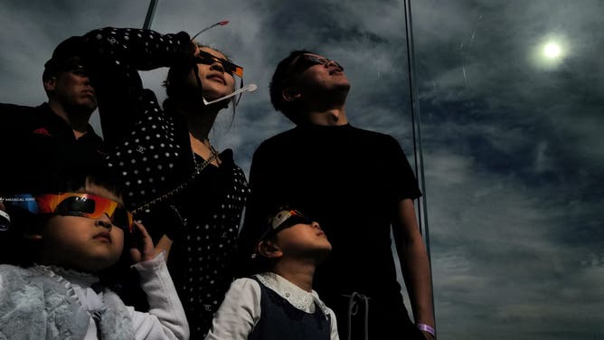 A woman looks toward the sky at the 'Edge at Hudson Yards' observation deck during a total solar eclipse across North America, in New York City on April 8, 2024. This year's path of totality is 115 miles (185 kilometers) wide and home to nearly 32 million Americans, with an additional 150 million living less than 200 miles from the strip. The next total solar eclipse that can be seen from a large part of North America won't come around until 2044.
