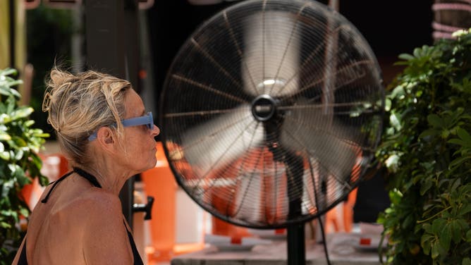 MIAMI, FLORIDA - JULY 31: A tourist cools off in front of a fan at one of the restaurants located on one of Miami Beach's main streets in Miami, Florida, United States, on July 31, 2025.