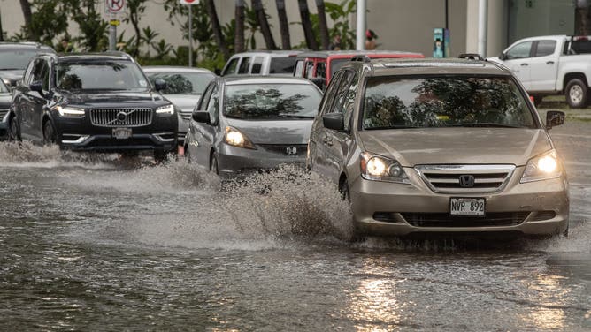 Vehicles make their way through a flooded intersection in front of the Hawaii Convention Center in Honolulu, Hawaii, on August 16, 2026. Hurricane Lala was pulling away from Hawaii's Big Island early Sunday, as heavy rain and strong winds struck the US Pacific state and officials warned of potentially dangerous flooding. The heavy rain and flood risk will then spread westward across the island chain on Sunday, according to the NHC.