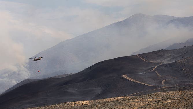 RENO, NEVADA - AUGUST 23: A firefighting equipped helicopter flies over the Hawk Fire on August 23, 2026 in Reno, Nevada.