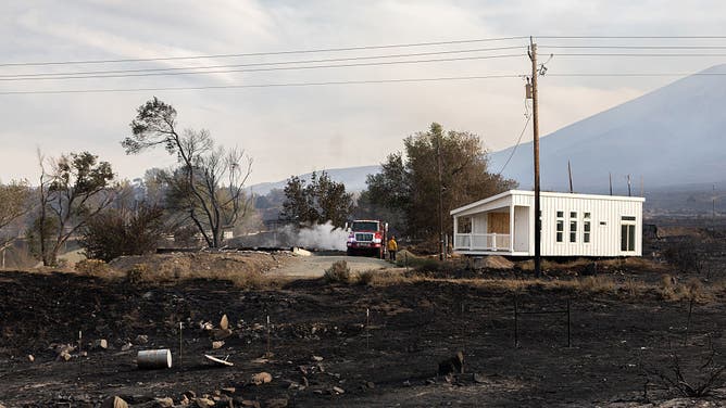 RENO, NEVADA - AUGUST 23: Firefighters spray water on a burned structure during the Hawk Fire on August 23, 2026 in Reno, Nevada.