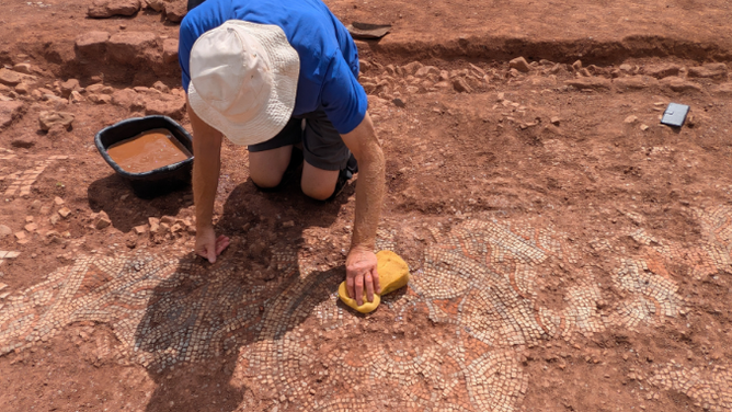 Archeologists and students clean off the mosaic.