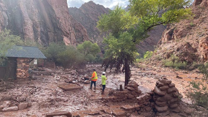 Crews walk through the damage and debris left behind by flooding.