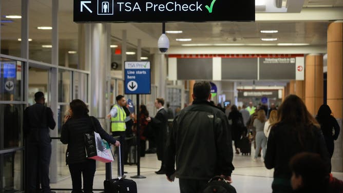 Travelers pass under a sign pointing toward a Transportation Security Administration (TSA) Pre-Check checkpoint at Hartsfield-Jackson Atlanta International Airport in Atlanta, Georgia, U.S., on Monday, Jan. 14, 2019.