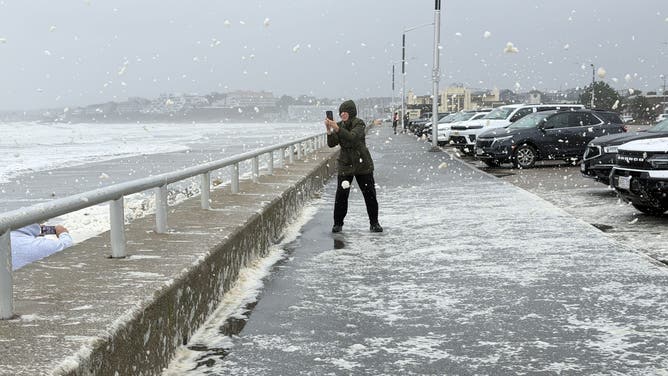 Sea foam flies up onto barrier wall above the beach in Hull, Massachusetts, as nor'easter causes blasting winds in New England.