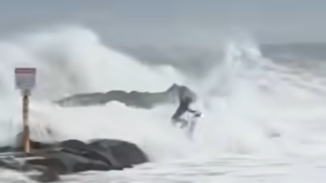 Surfer dives back into the water as rough waves create dangerous conditions.