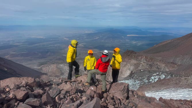 A group of rescuers stand along the side of the mountain.
