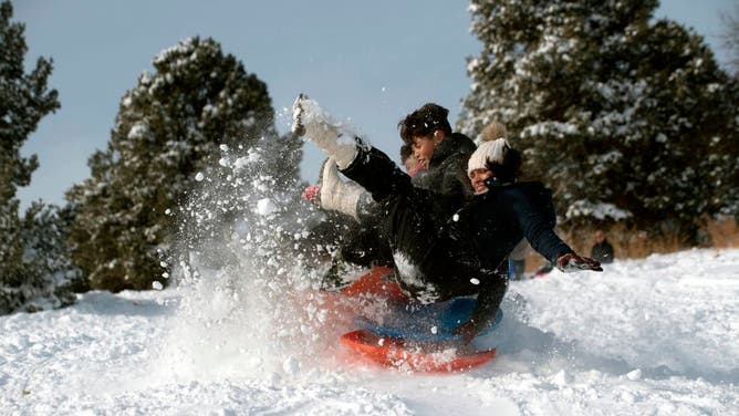 Perla Zapata (R) her cousin Kevin Zapata (C,) and family members catch air while sledding at Ruby Hill Park in Denver, Colorado on November 27, 2019. - A pair of storms packing heavy snow and hurricane-force winds left tens of thousands without power in the United States on November 27, 2019, and wreaked havoc for Americans traveling for the Thanksgiving holiday.