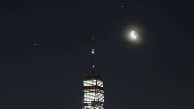 JERSEY CITY, NJ - MARCH 18: Saturn, Jupiter and Mars along with a crescent moon rise in the pre-dawn sky above One World Trade Center on March 18, 2020 as seen from Jersey City, New Jersey.