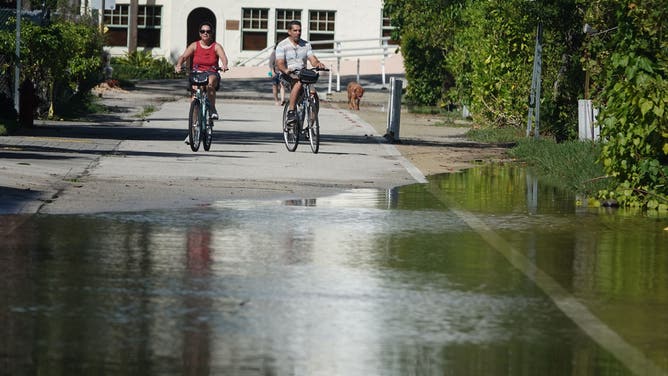 Fort Lauderdale residents navigate some water-filled roadways amid the king tides on Sept. 26, 2022, along Southeast Second Street.