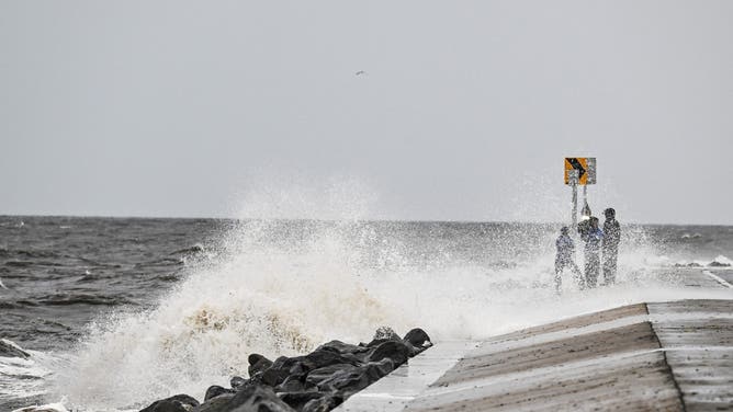 People stand on the shoreline ahead of the arrival of Hurricane Helene in Alligator Point, Florida, on September 26, 2024.