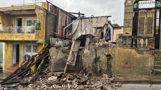 TOPSHOT - Men salvage belongings from the rubble of her their home after it collapsed during Hurricane Melissa's passage through Santiago de Cuba, Cuba, on October 29, 2025.