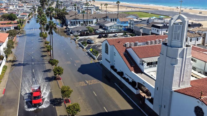 NEWPORT BEACH, CALIFORNIA - OCTOBER 09: In an aerial view, an emergency vehicle drives through coastal floodwaters amid strong waves and high tides generated by Tropical Storm Rachel on October 9, 2026 in Newport Beach, California.