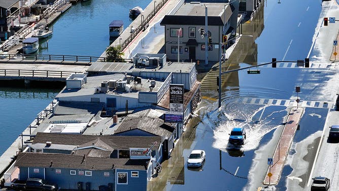 Huntington Beach, CA - October 26: Sea water floods on to Pacific Coast Highway during high tide in Sunset Beach on Monday, October 26, 2026.