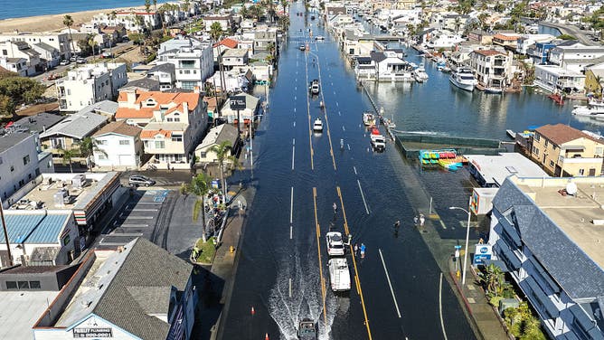 HUNTINGTON BEACH, CALIFORNIA - OCTOBER 27: In an aerial view, a motorist drives through coastal floodwaters during high tide flooding along the closed Pacific Coast Highway in the Sunset Beach community on October 27, 2026 in Huntington Beach, California.