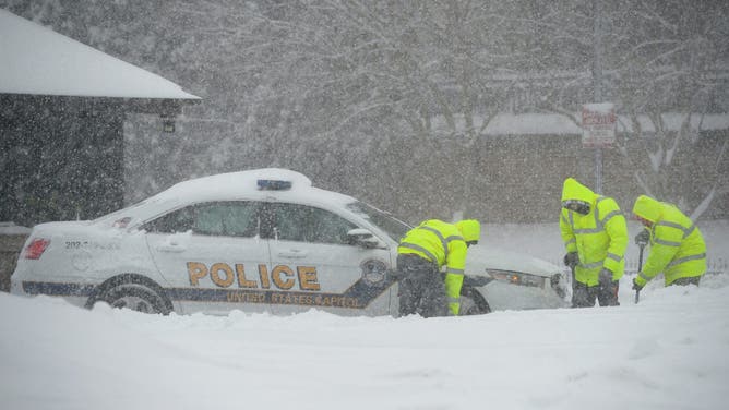 Workers dig out a Capitol police car on Capitol Hill in Washington on January 23, 2016.