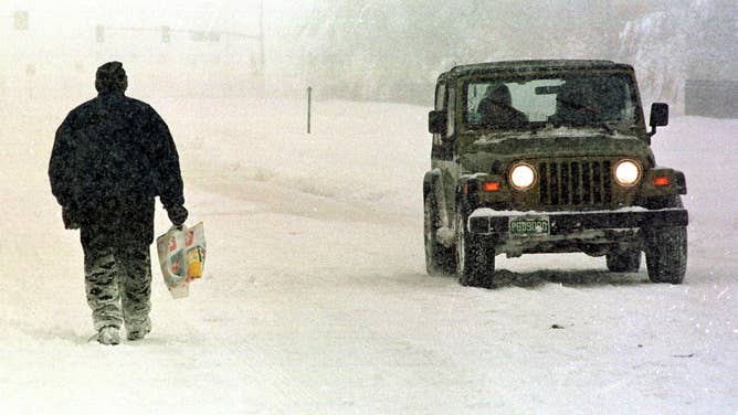 Ron Williams (L) is passed by a Jeep as he walks home from the grocery store in Denver, CO 25 October.