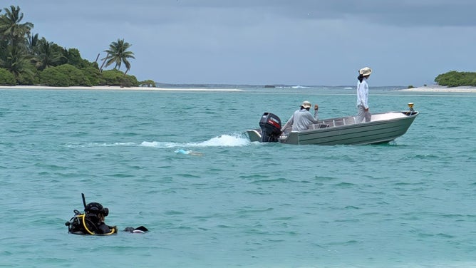 Scuba divers swim along the lagoon coast where the Taraia Object lies.